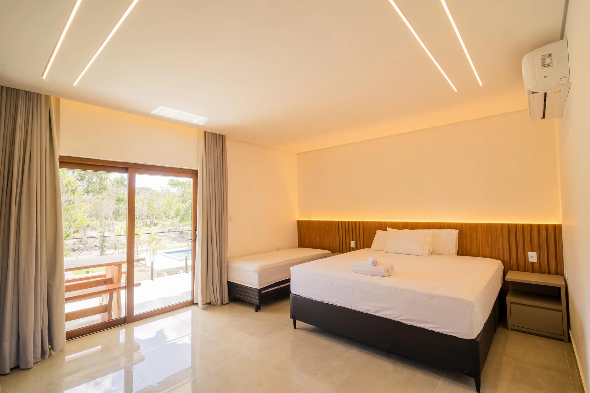 Suíte com cama e porta para a varanda no Residencial Marinho, Arraial d’Ajuda.