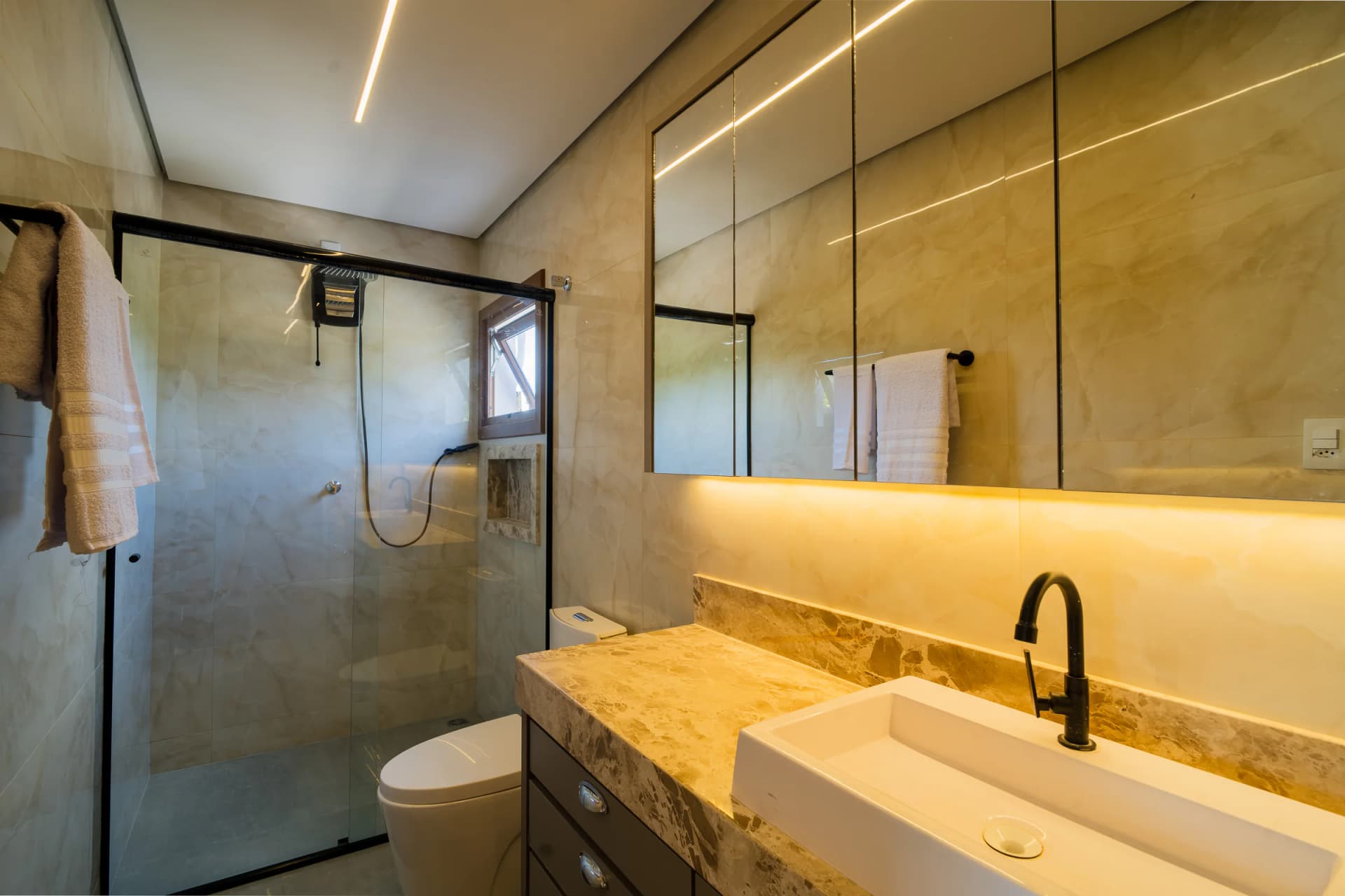 Banheiro com bancada, espelho e box no Residencial Marinho, Arraial d’Ajuda.