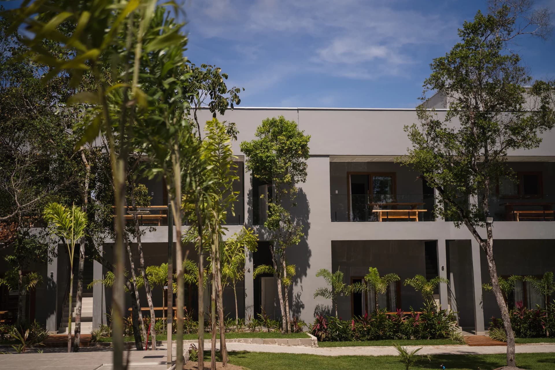 Fachada das suítes entre árvores no Residencial Marinho, Arraial d’Ajuda.